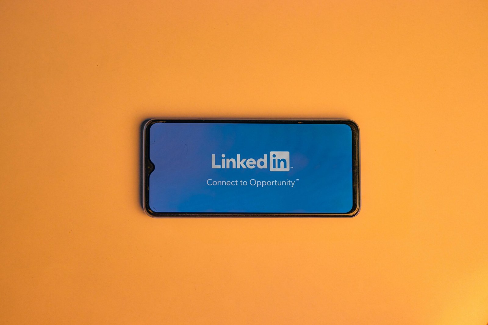 Smartphone showing LinkedIn login on vibrant orange background, symbolizing connectivity.